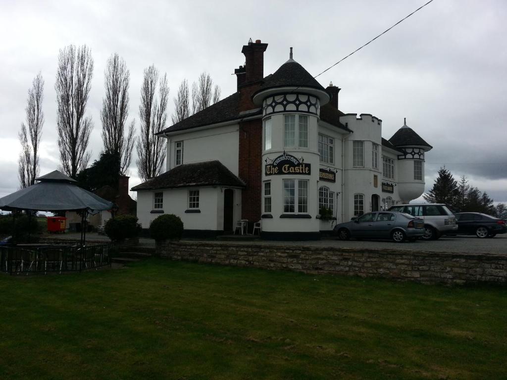 una gran casa blanca con coches estacionados frente a ella en The Castle Inn, en Market Drayton