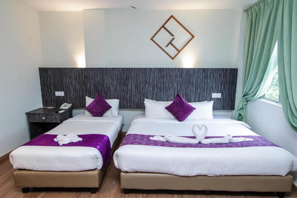 two beds in a hotel room with purple pillows at Salsa Resort Langkawi By Casa Loma in Pantai Cenang