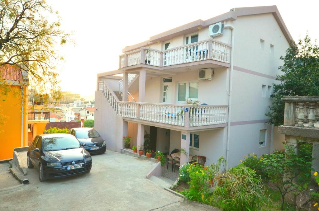 un edificio con dos coches estacionados en un estacionamiento en Guesthouse Apartments Čenić, en Budva