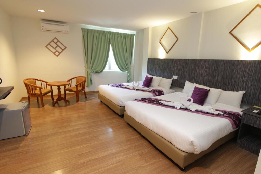 a hotel room with two beds and a table at Salsa Resort Langkawi By Casa Loma in Pantai Cenang