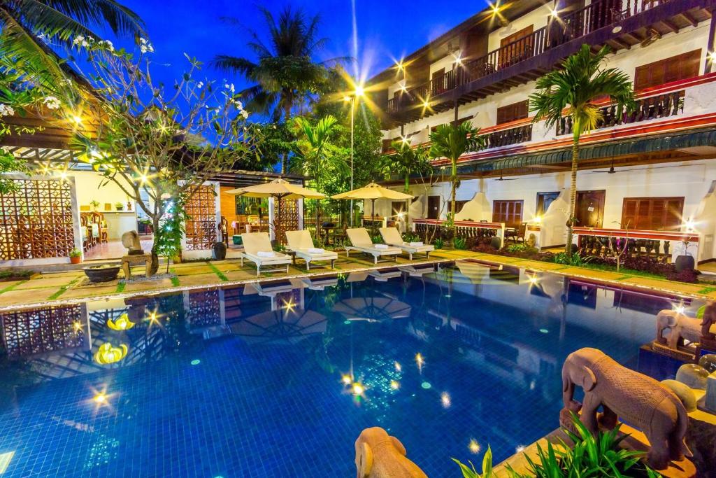 a swimming pool in front of a hotel at night at BayStone Resort in Siem Reap