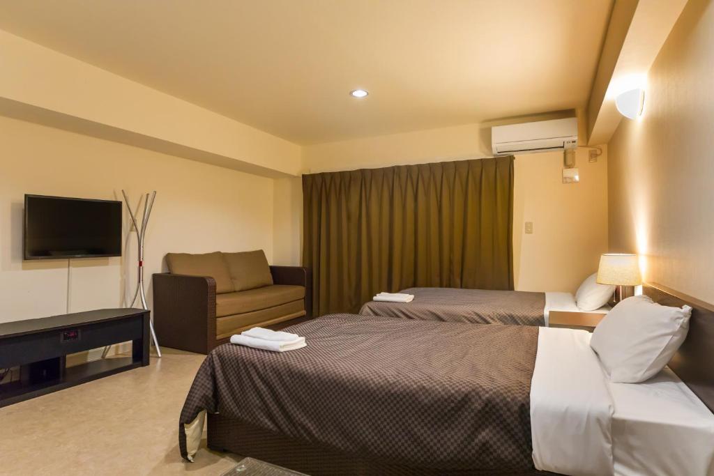 a hotel room with two beds and a couch at Condominium Hotel Monpa in Chatan