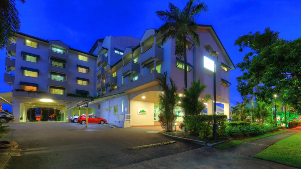 ein Gebäude mit einem Auto auf einem Parkplatz in der Unterkunft Cairns Sheridan Hotel in Cairns