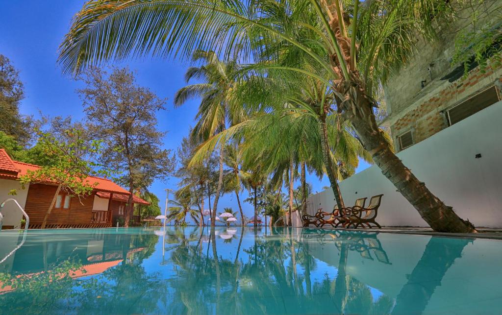 a swimming pool with palm trees next to a building at Arugambay PodBay in Arugam Bay