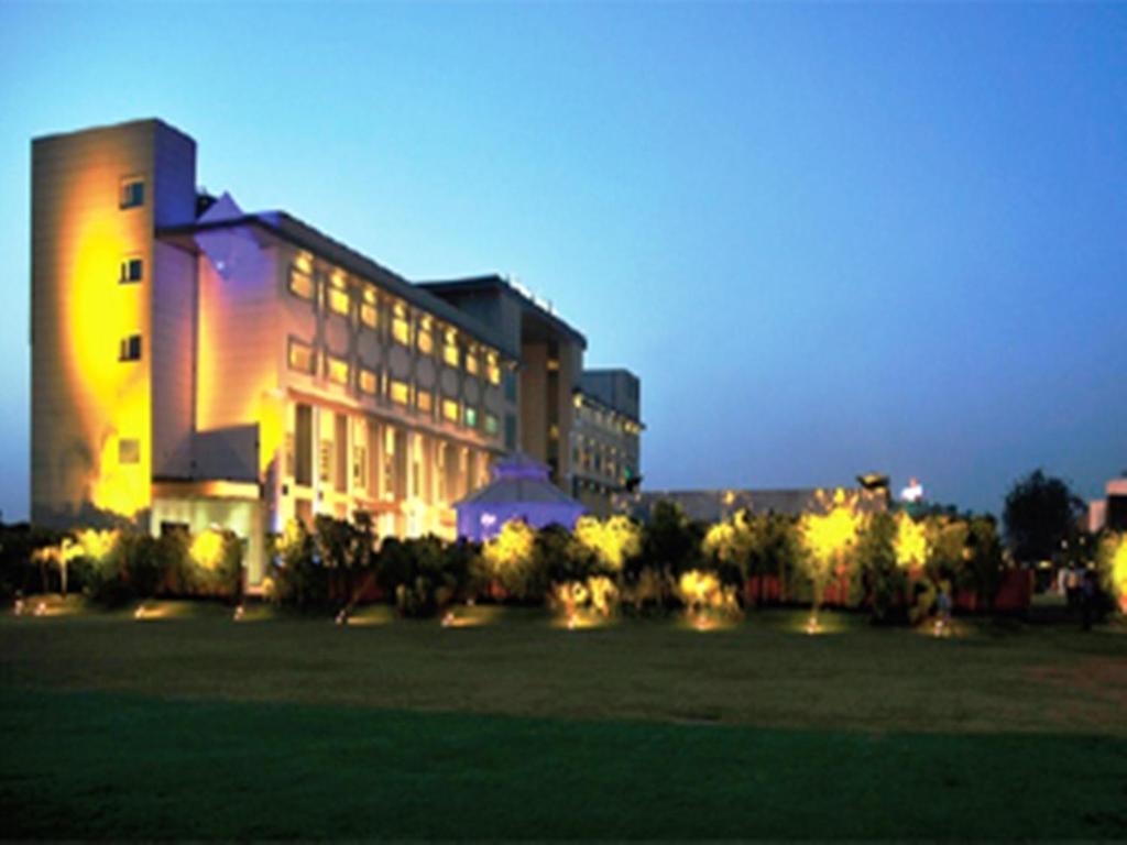 a large building with lights in front of a field at Brijwasi Lands Inn in Mathura