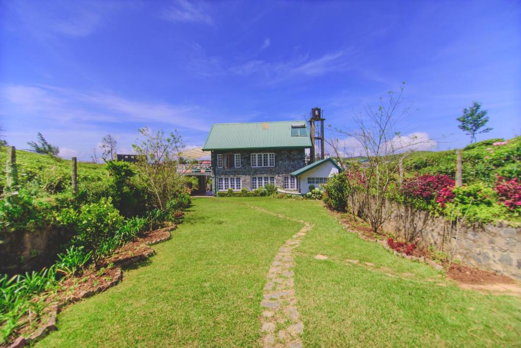 a house with a green roof and a grass yard at Sarah Cottage Nuwara Eliya in Nuwara Eliya