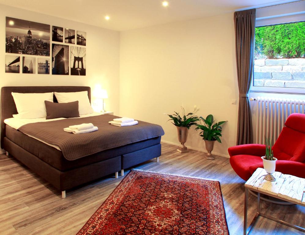 a bedroom with a bed and a red chair at Ferienwohnung Roxana - am Bodensee in Friedrichshafen