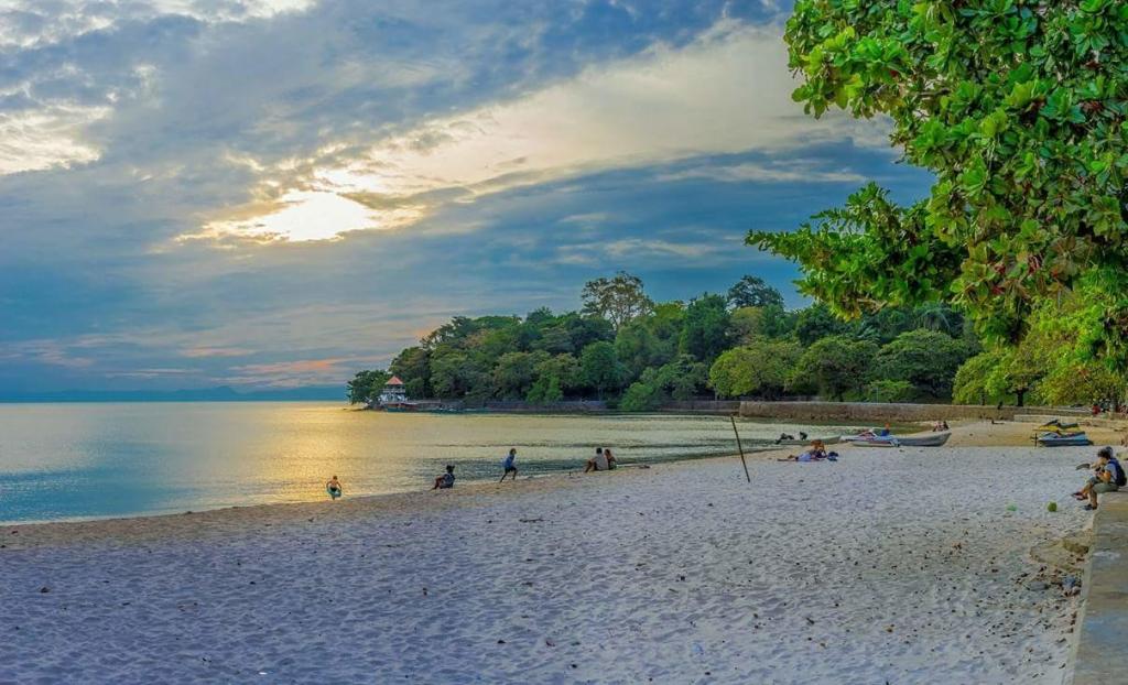 a group of people on a beach near the water at Hotel de la Plage in Kep