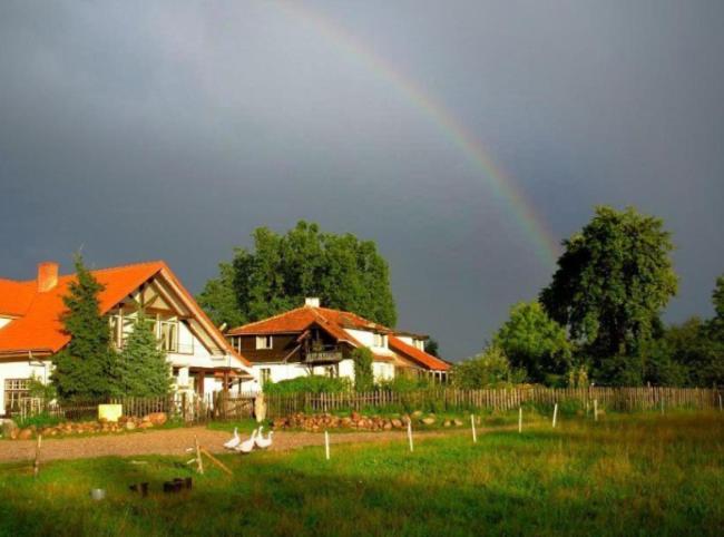 un arco iris en el cielo sobre una casa con un patio en Pension Jakubowo, en Jakubowo