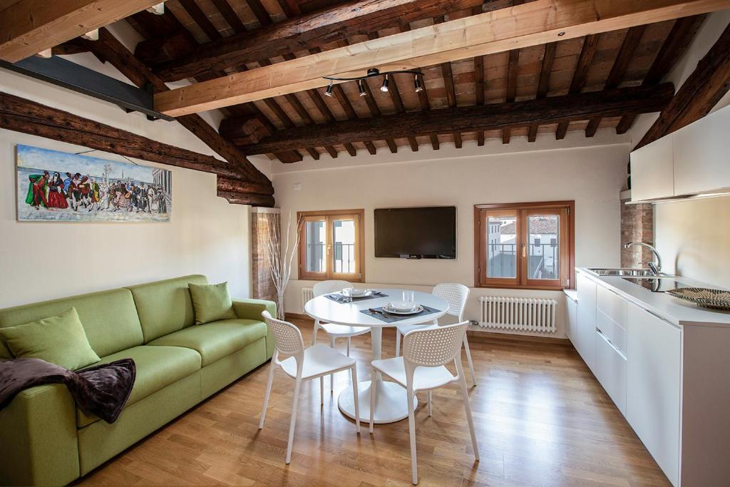 een woonkamer met een groene bank en een tafel bij Loft Mirano (Alloggi alla Campana) in Mirano