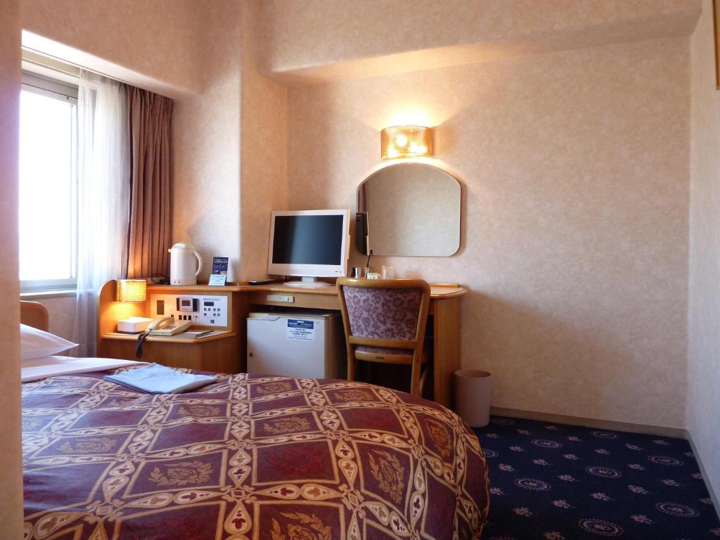 een hotelkamer met een bed en een bureau met een computer bij Hotel New Green Tsubame Sanjo in Sanjo