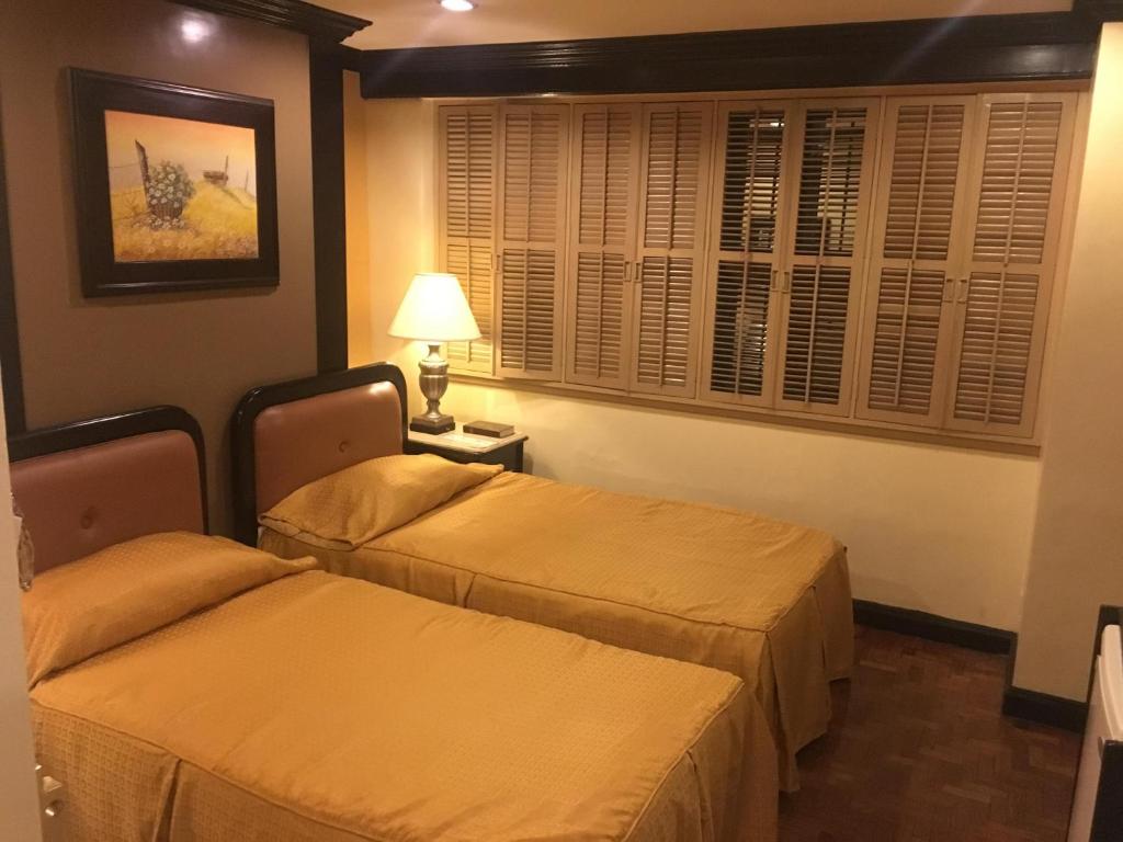 a hotel room with two beds and a lamp at Lourdes Suites in Manila