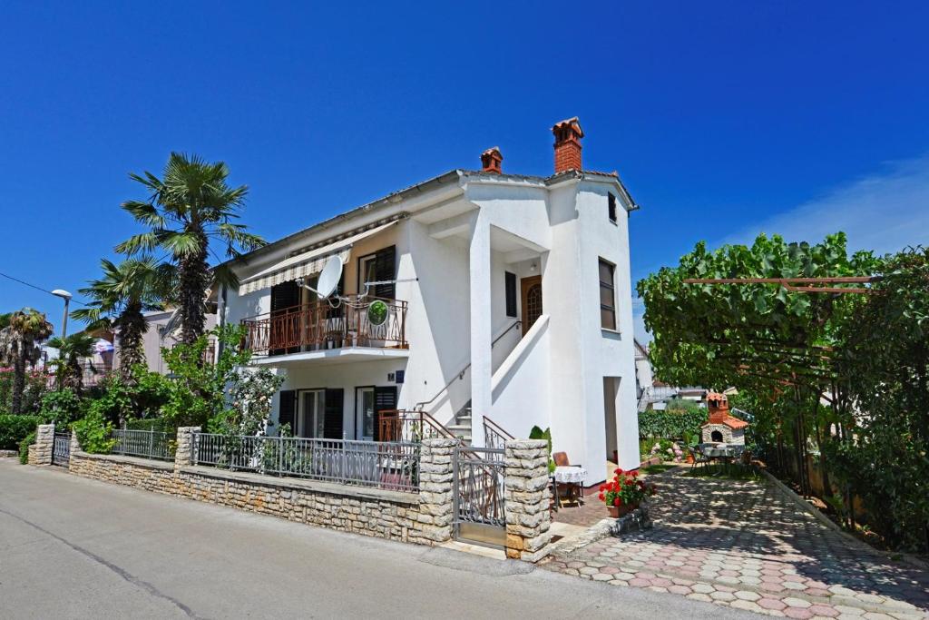 a white house with a balcony on a street at Apartment Complex Nevia in Poreč