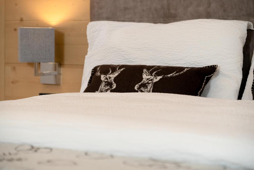 a white bed with a black pillow with deer on it at GARNI' Margherita in Predazzo