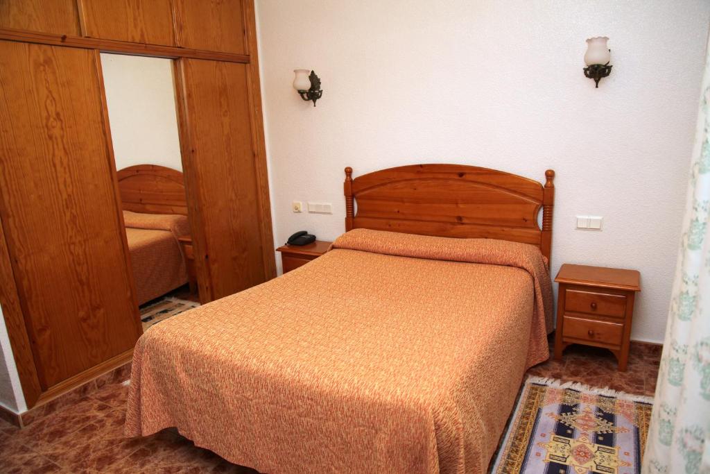El Alquián的住宿－Hotel Los Arcos，一间卧室配有一张带木制床头板的床