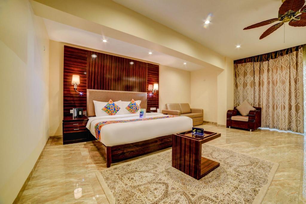 1 dormitorio grande con 1 cama grande y 1 silla en FabHotel Prime Sarala Crown With Pool, Calangute Beach en Calangute