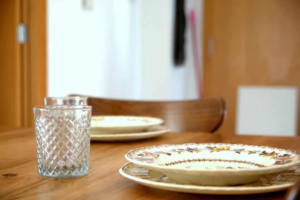 une table en bois avec deux plaques et un verre dans l'établissement Villa Bleuor, à Arenys de Mar