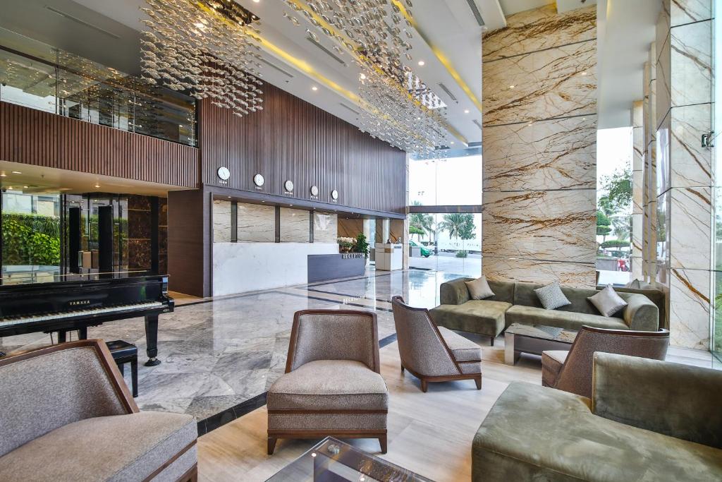 A spacious marble lobby with lounge seating, a piano, and a decorative ceiling installation.