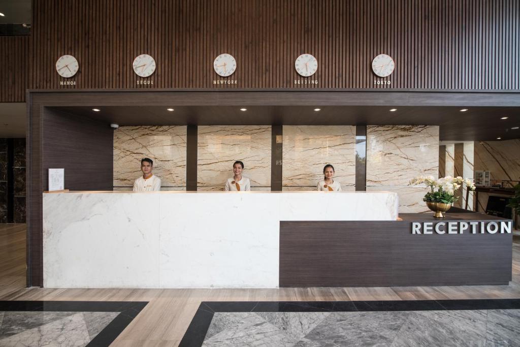 The main reception counter with three staff members and clocks above it.
