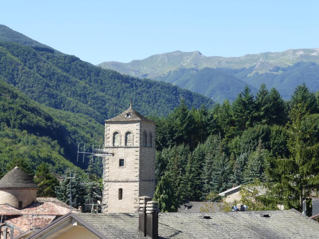 einen Uhrturm auf einem Gebäude mit Bergen im Hintergrund in der Unterkunft I Faggi Rossi in Fanano