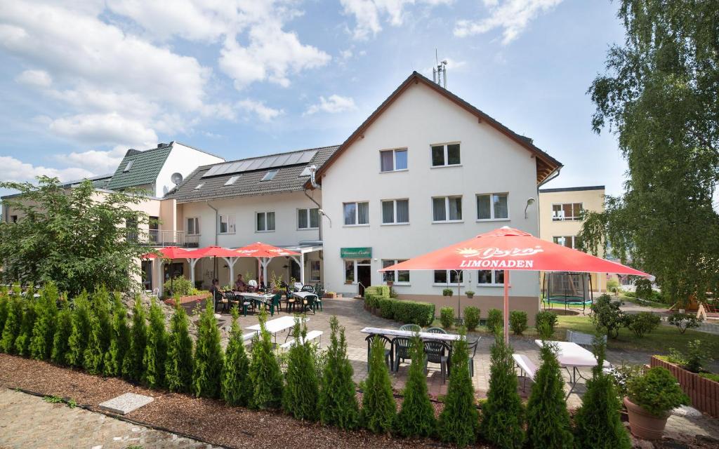 a hotel with tables and umbrellas in front of a building at Berghotel Tambach in Tambach-Dietharz