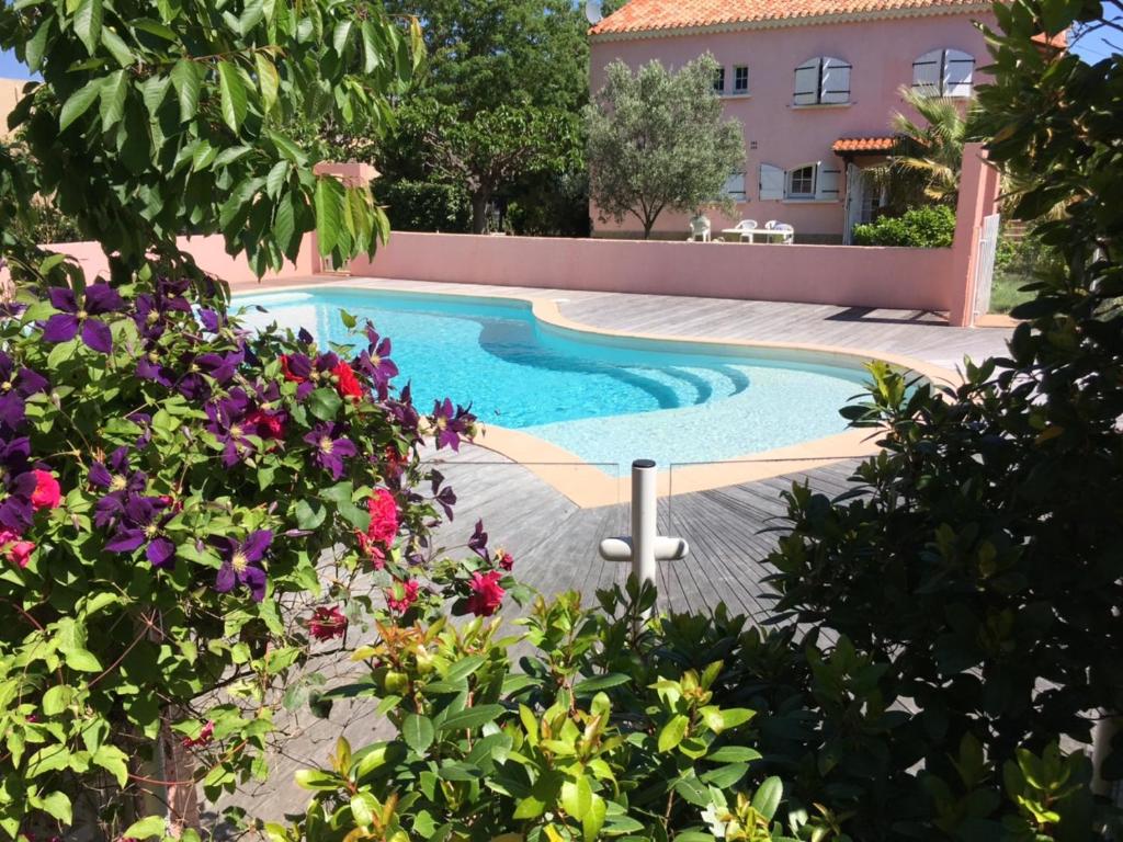 een zwembad voor een huis met bloemen bij Jm Vacances Serignan in Sérignan