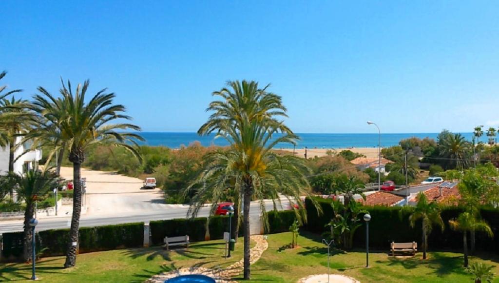 uma vista para uma rua com palmeiras e o oceano em Sueño de Denia III VAC007 Denirent em Denia