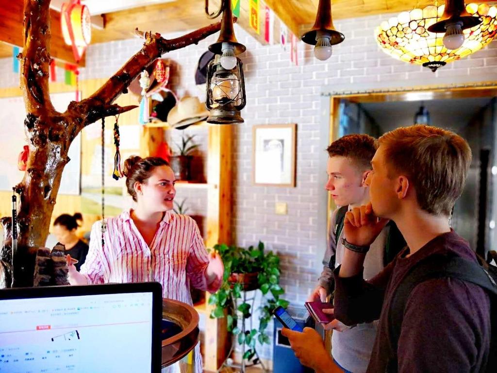 a group of people standing in a bar looking at a computer at The Silk Road Travelers Hostel in Zhangye