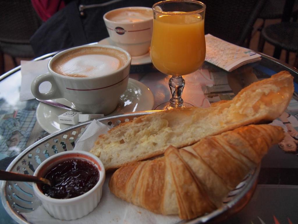 a plate of bread and coffee and a glass of orange juice at Villa Tenko in Ouagadougou