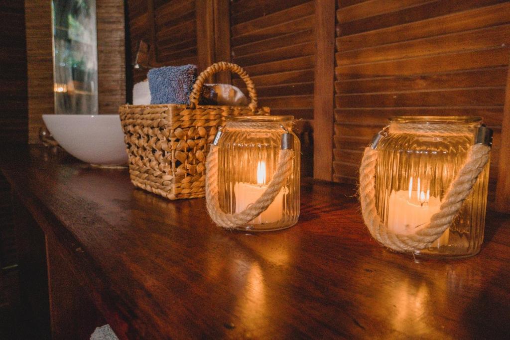 two candles in glass jars on a table with a basket at Oka Da Mata in Pipa