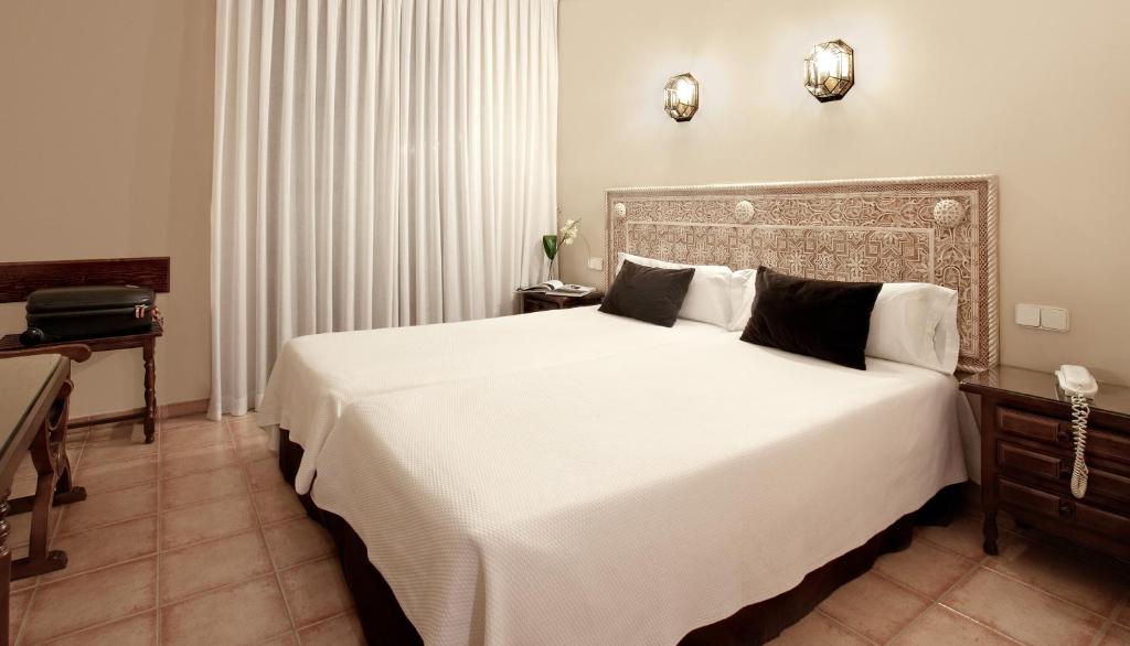 - une chambre dotée d'un grand lit avec des draps et des oreillers blancs dans l'établissement Princesa Galiana, à Tolède