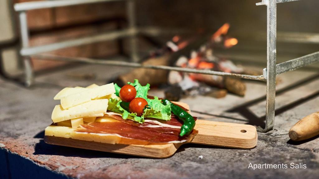 a sandwich with cheese and tomatoes on a cutting board at Salis Apartments in Vrsi