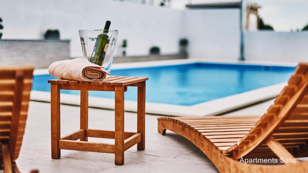 a table with a drink on it next to a pool at Salis Apartments in Vrsi