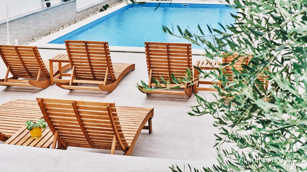 a row of chairs sitting next to a swimming pool at Salis Apartments in Vrsi