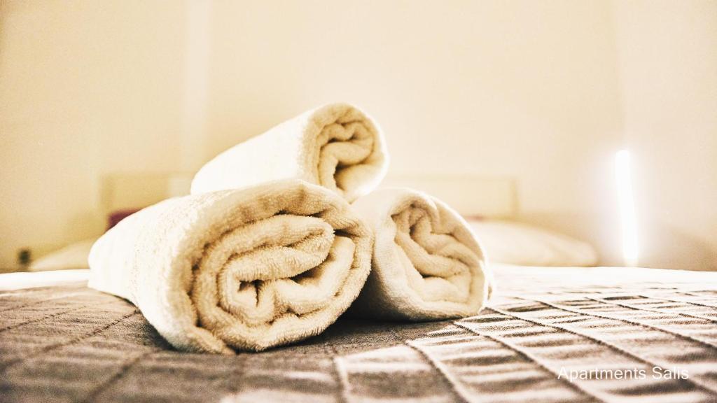 a pile of towels sitting on top of a bed at Salis Apartments in Vrsi