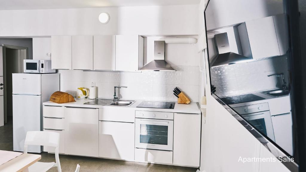 a white kitchen with a sink and a stove at Salis Apartments in Vrsi