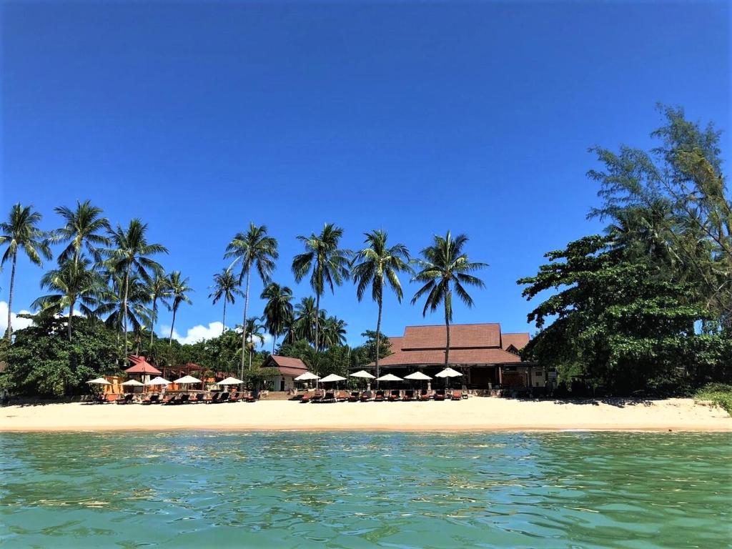 a beach with chairs and umbrellas and palm trees at Kanok Buri Resort in Lipa Noi
