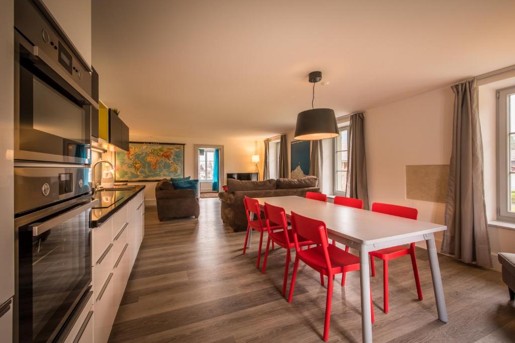 Dependance Penthouse في إنترلاكن: مطبخ وغرفة معيشة مع طاولة وكراسي حمراء