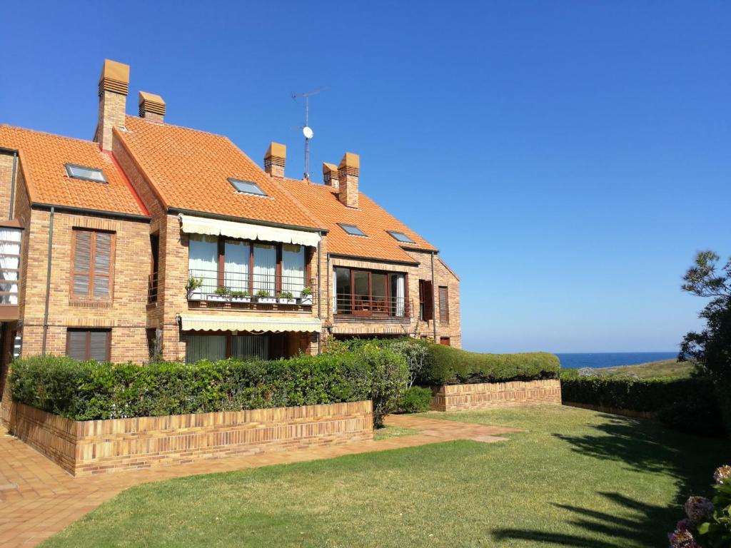 a large brick house with the ocean in the background at Noja Playamar Apartment in Noja