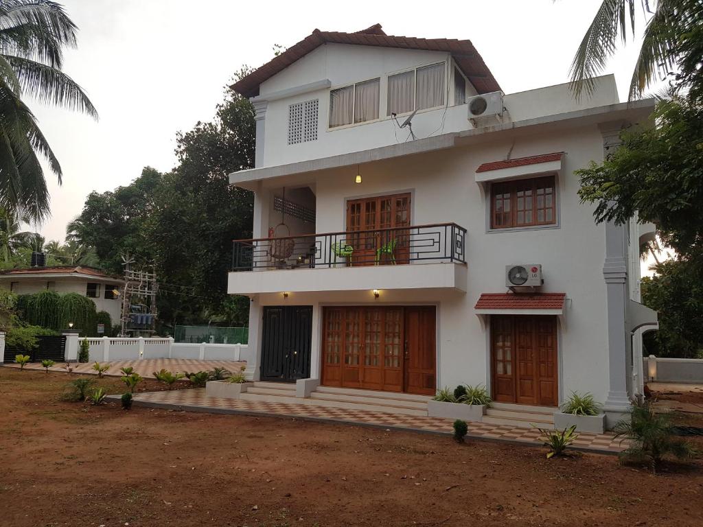 a white house with a balcony on top of it at Casa Arvana Near Calangute Beach in Calangute
