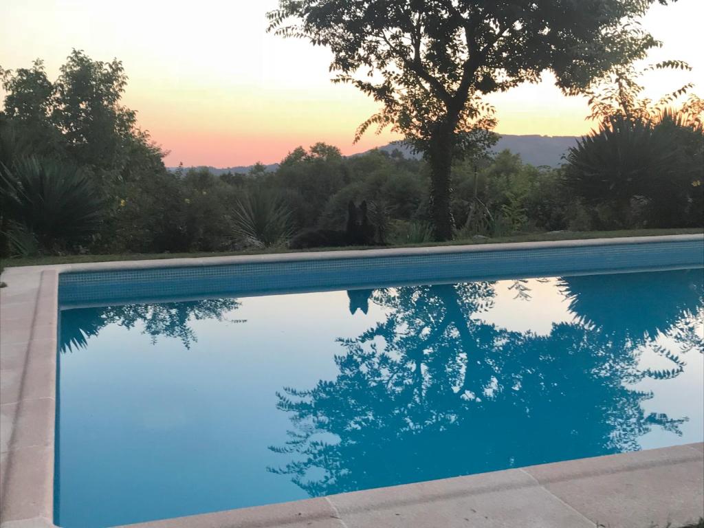 una piscina azul con puesta de sol en el fondo en Quinta Casa da Fonte en Vieira do Minho