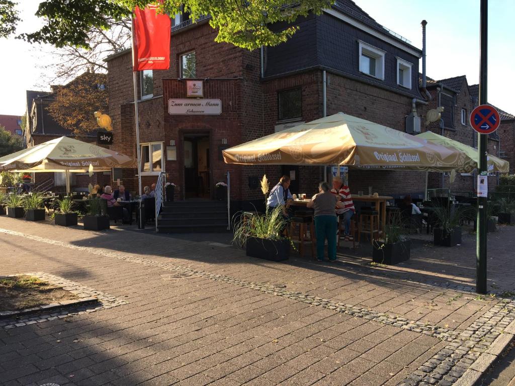 een groep mensen die buiten een gebouw onder een paraplu staan bij Zum armen Mann in Düsseldorf