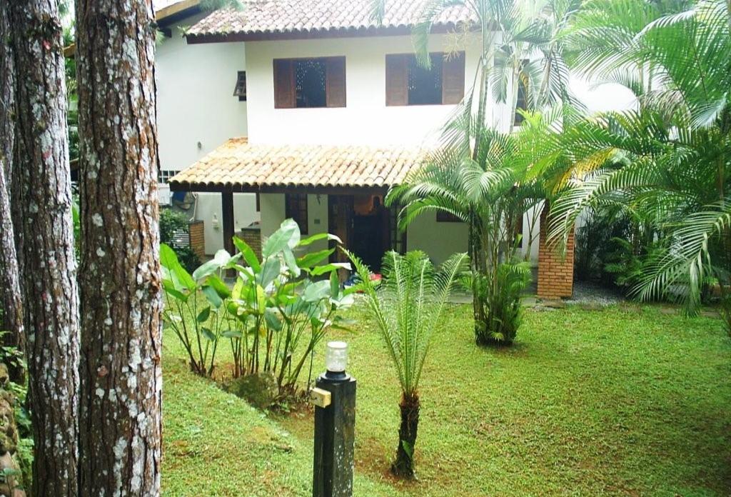 ein Haus in einem Garten mit einer Palme in der Unterkunft CASA CONDOMÍNIO FECHADO in Boicucanga