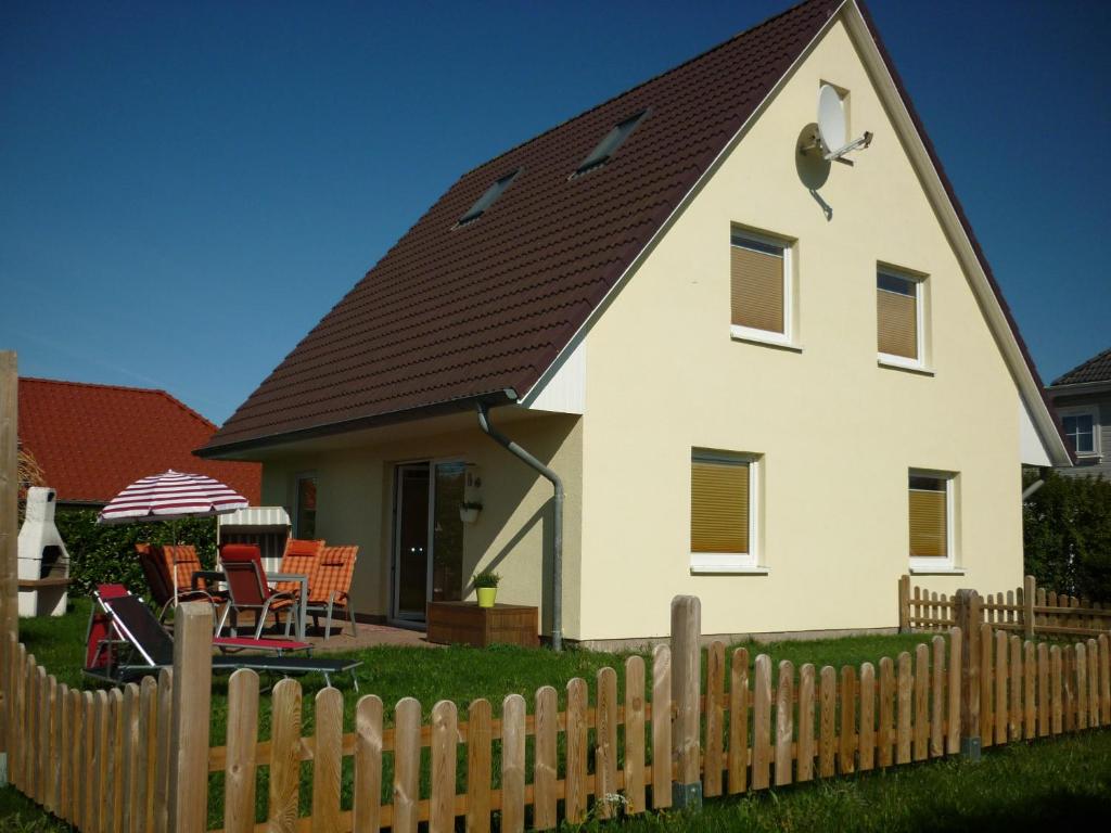 a white house with a brown roof behind a fence at Ferienhaus Kozian in Kühlungsborn