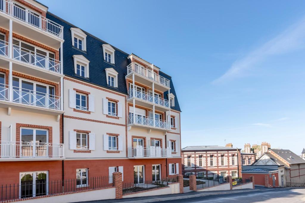 ein Apartmenthaus mit Balkon auf einer Straße in der Unterkunft Villa Médicis Trouville-sur-mer in Trouville-sur-Mer