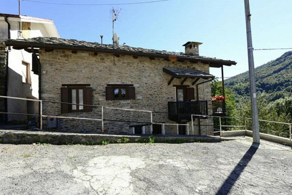 una piccola casa in pietra con una collina sullo sfondo di Gran Paradiso ad Alpette