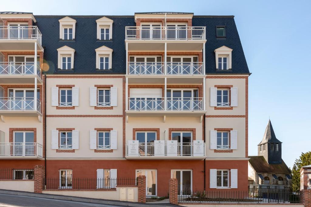 an apartment building with balconies and a clock tower at Villa Médicis Trouville-sur-mer in Trouville-sur-Mer
