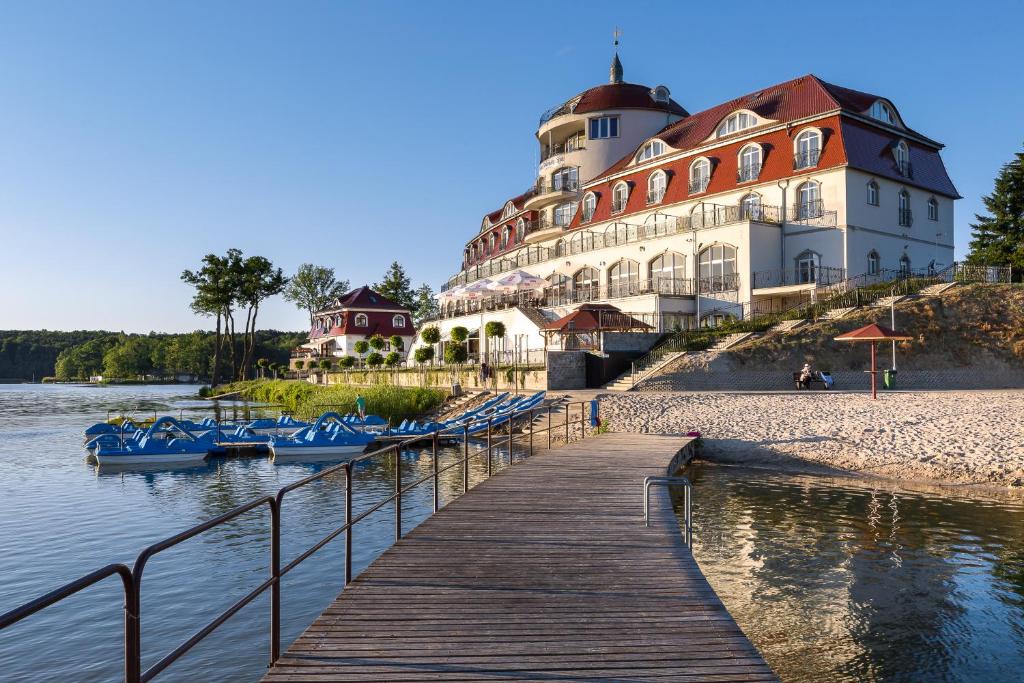a building next to a dock with boats in the water at Hotel Woiński Spa in Lubniewice