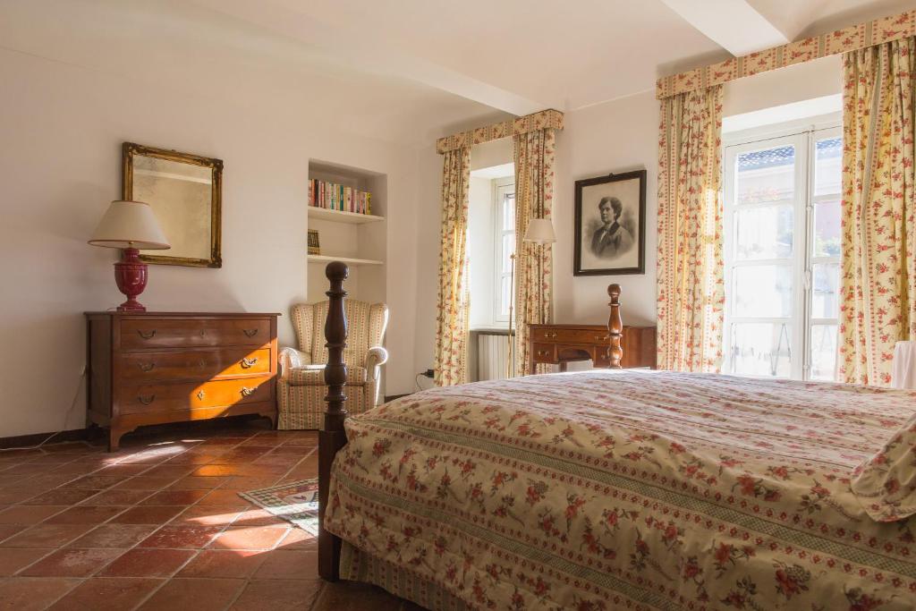 sypialnia z łóżkiem, komodą i oknami w obiekcie Villa Fiorita w mieście Castello di Annone