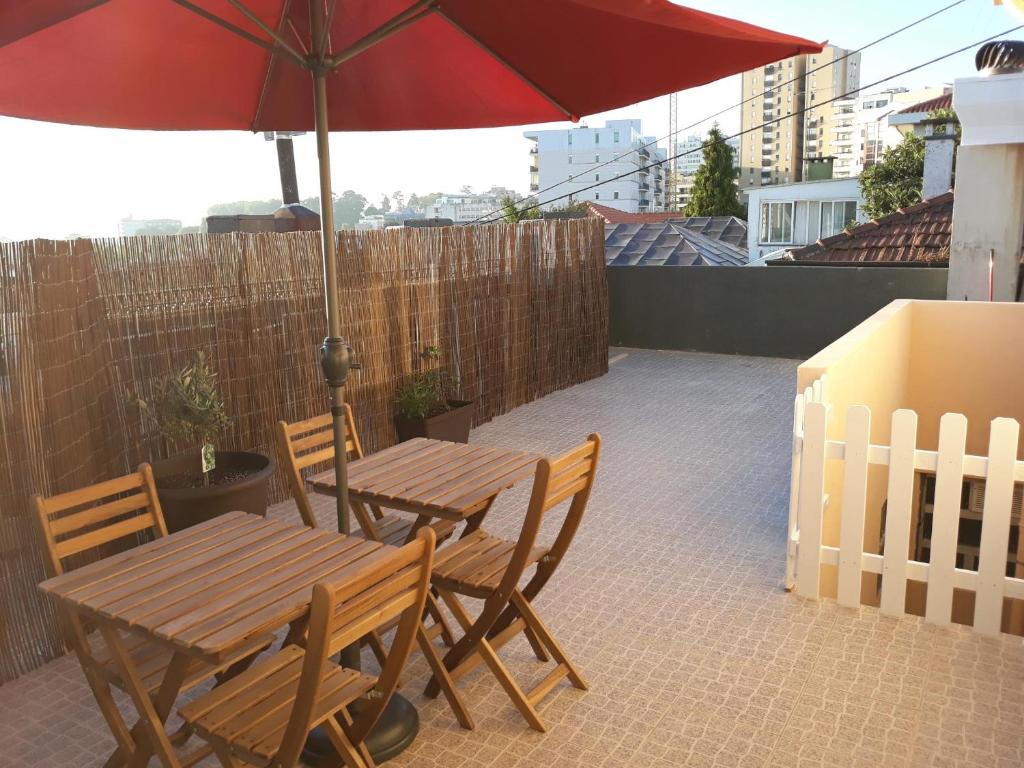 una mesa de madera y sillas con sombrilla en el patio en Maiahouse en Maia